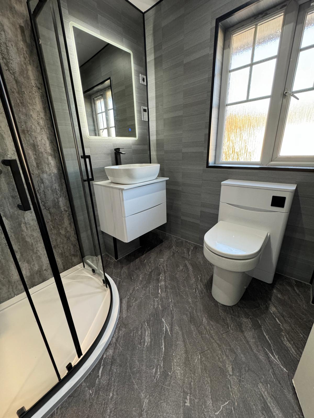 Modern grey wet wall bathroom with curved shower, vessel basin and backlit mirror